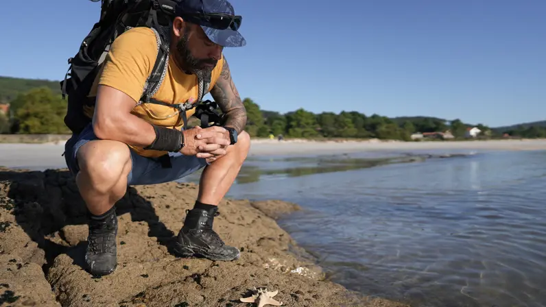 René zit gehurkt bij een zeester aan het water 