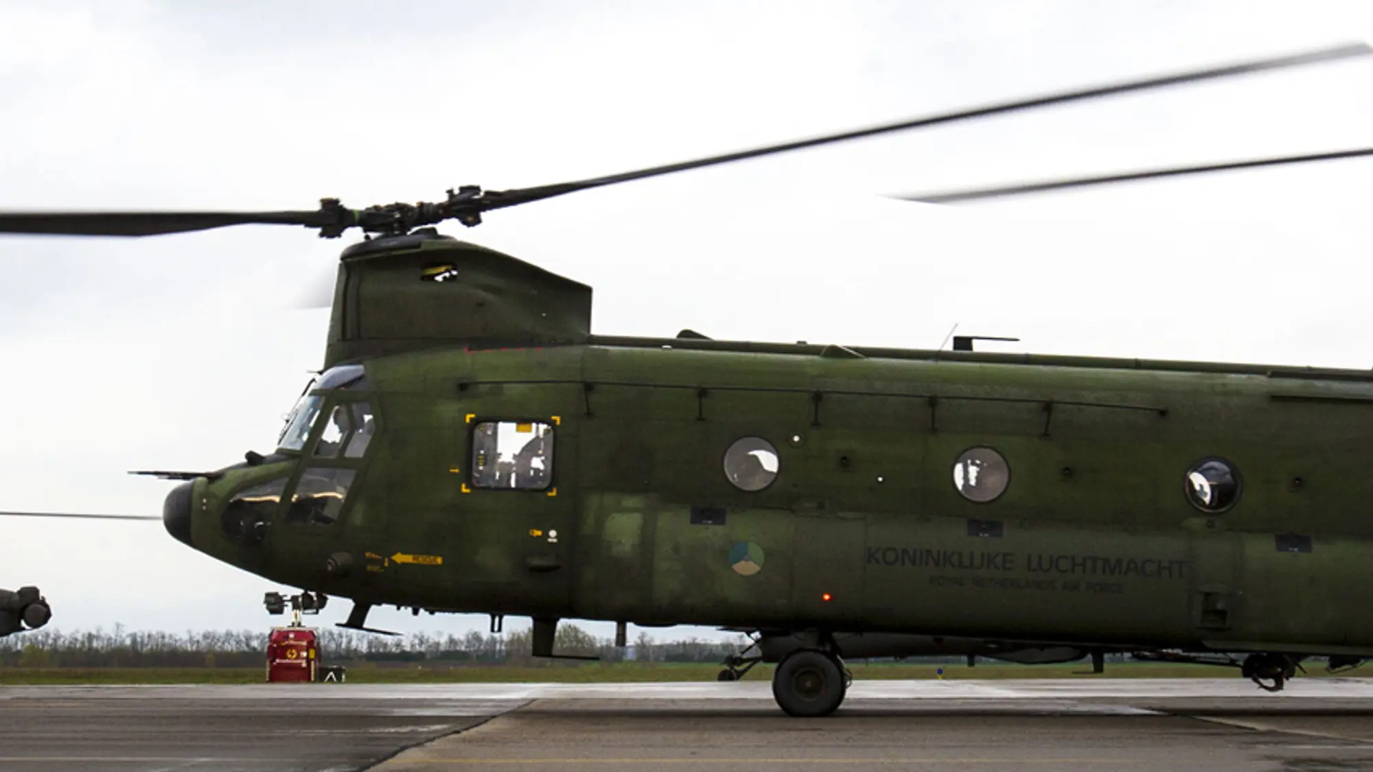 Chinook-transporthelikopter op de grond met op de achtergrond een Apache-gevechtshelikopter.