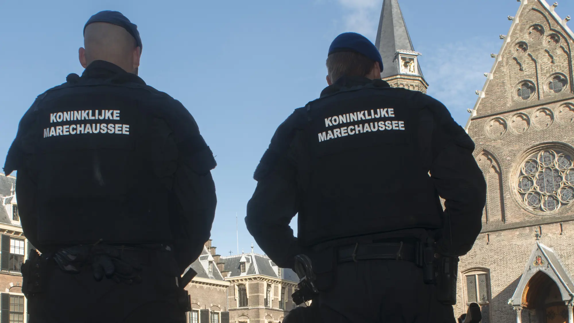 Drie medewerkers van de KMar staan op het Binnenhof in Den Haag.