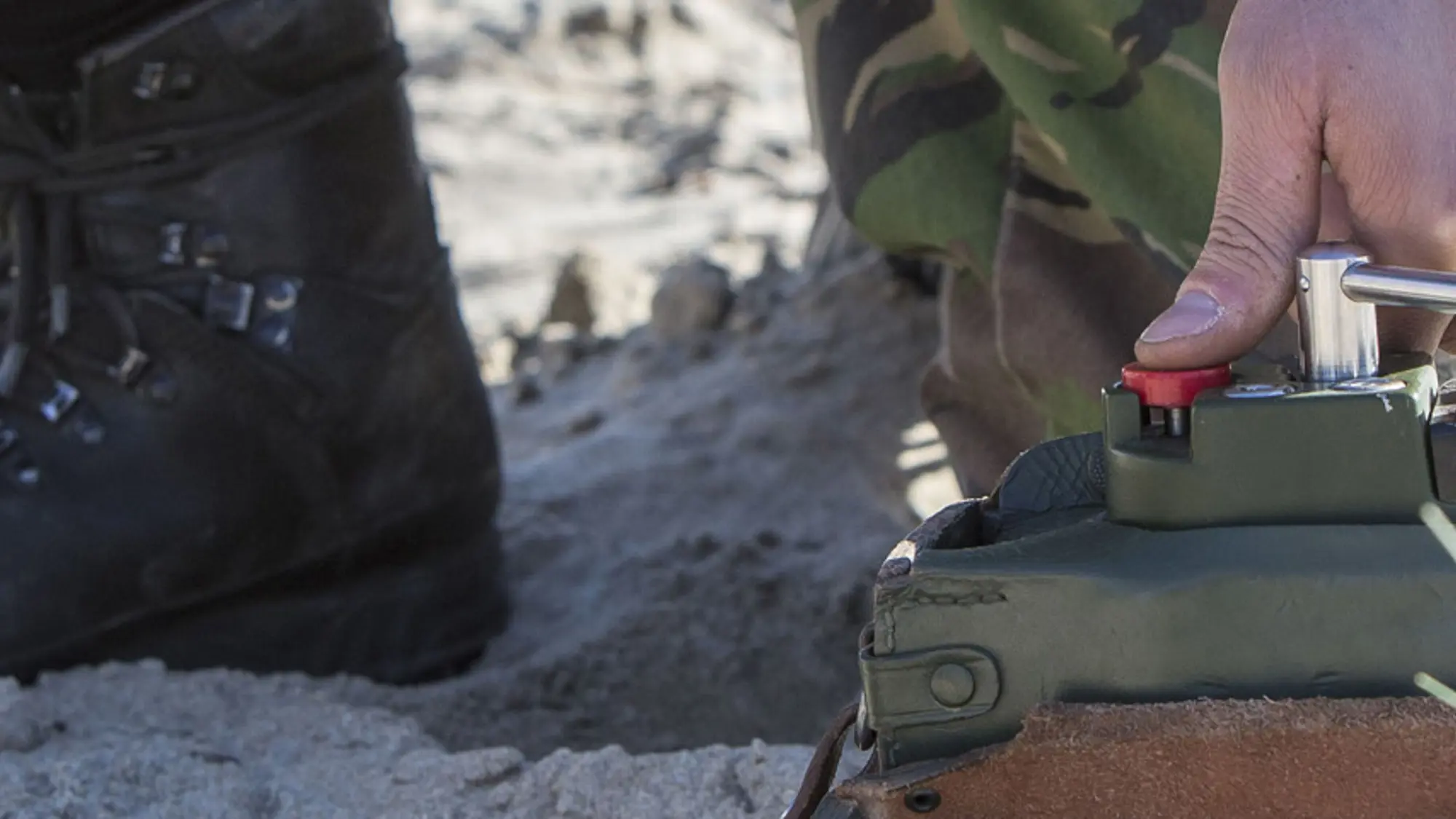 Militair drukt rode ontstekingsknop voor explosieven in om deze op afstand op te blazen.