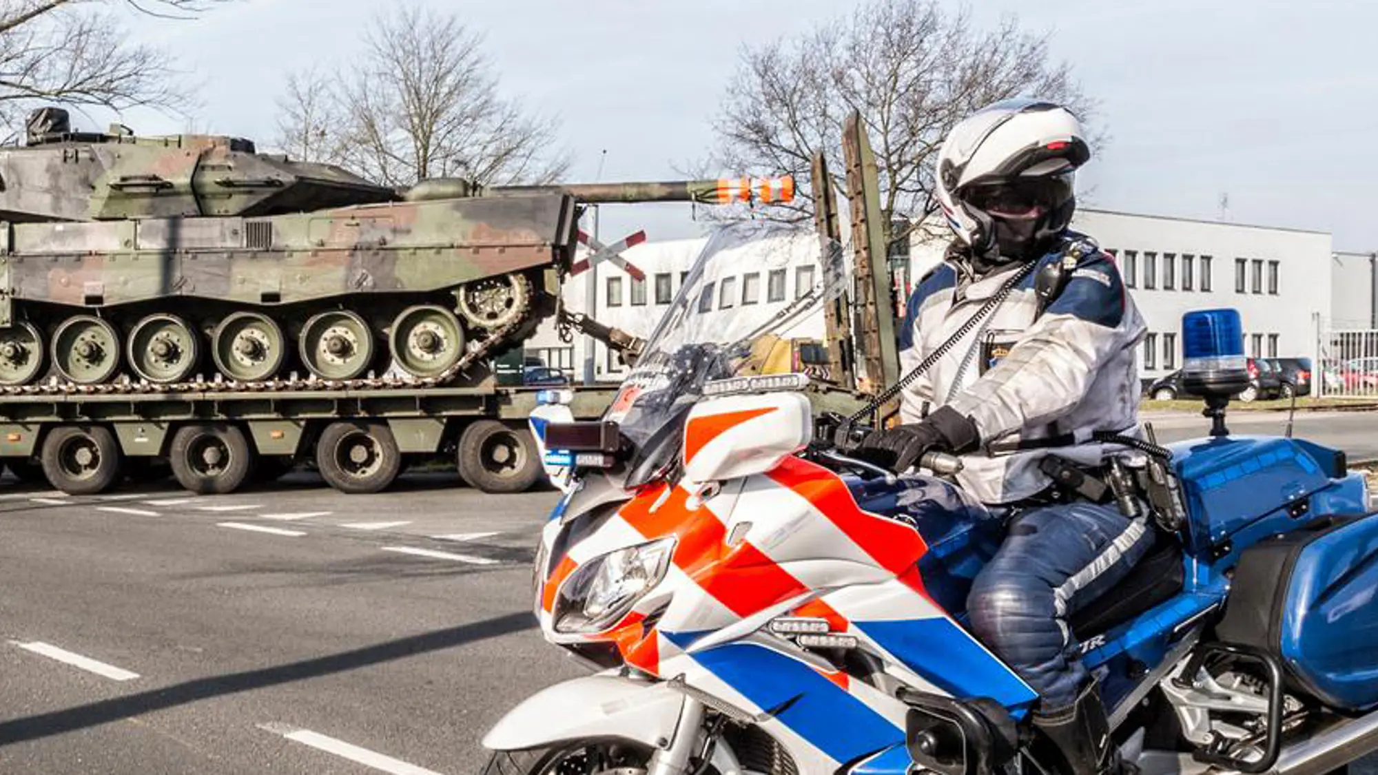 Motoragent van de KMar houdt verkeer tegen tijdens militaire colonne.
