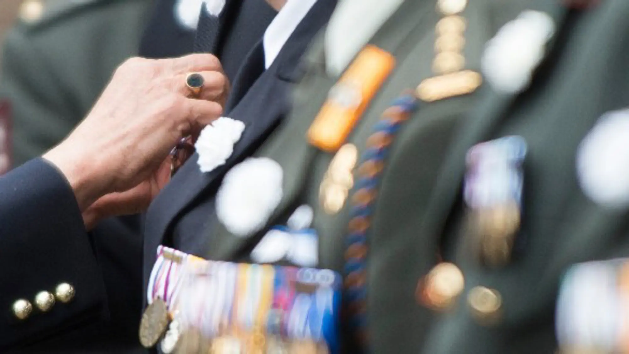 Close-up van de handen van een militair die andere militair onderscheiding opspeldt.