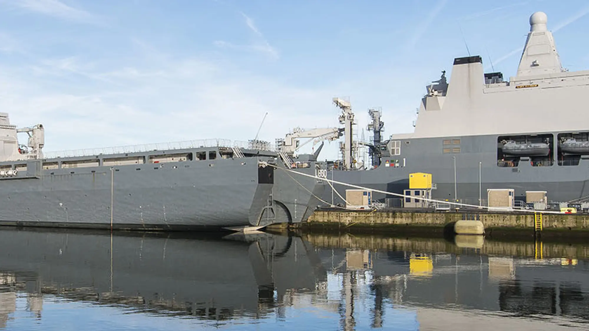Twee grote marineschepen liggen aan de kade in haven.