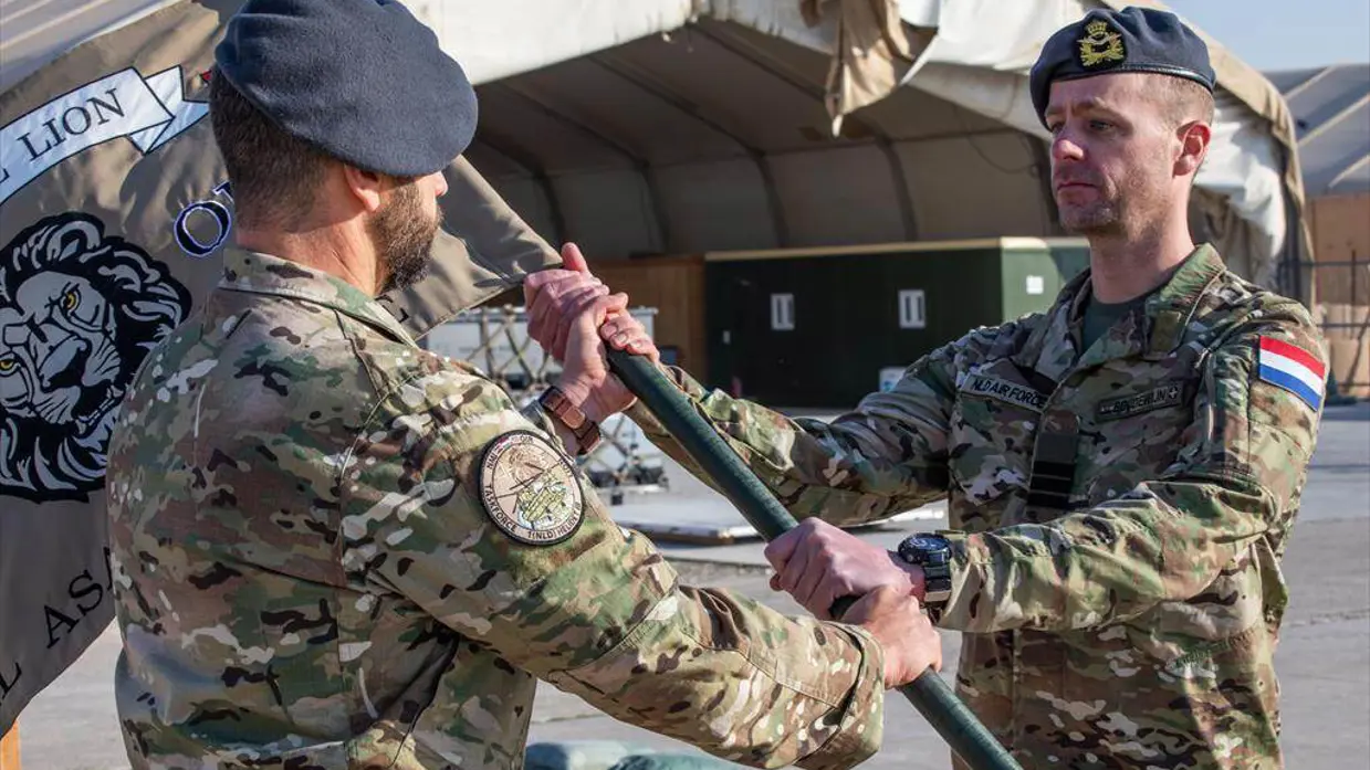Militair overhandigt vlag aan andere militair.