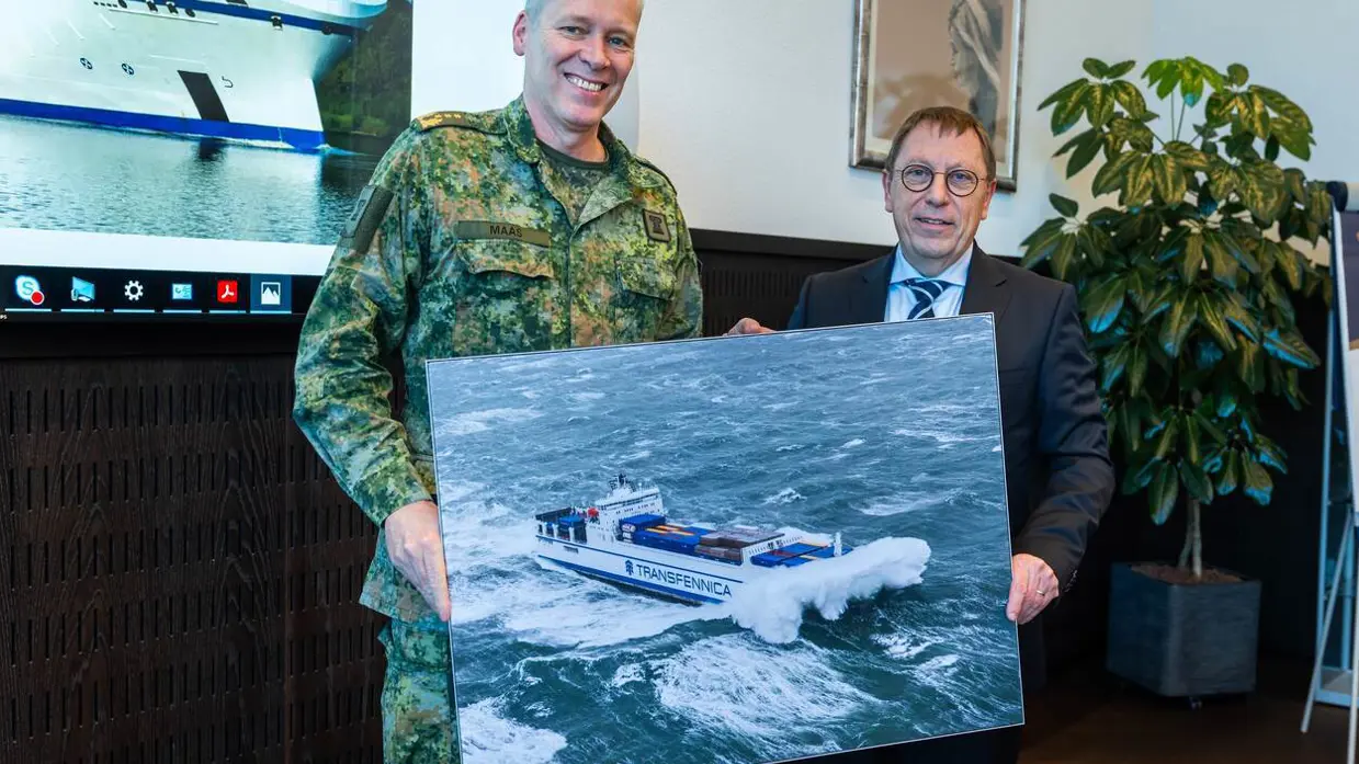 Luitenant-generaal Jan-Willem Maas en andere man houden bord vast waarop schip is verbeeld.