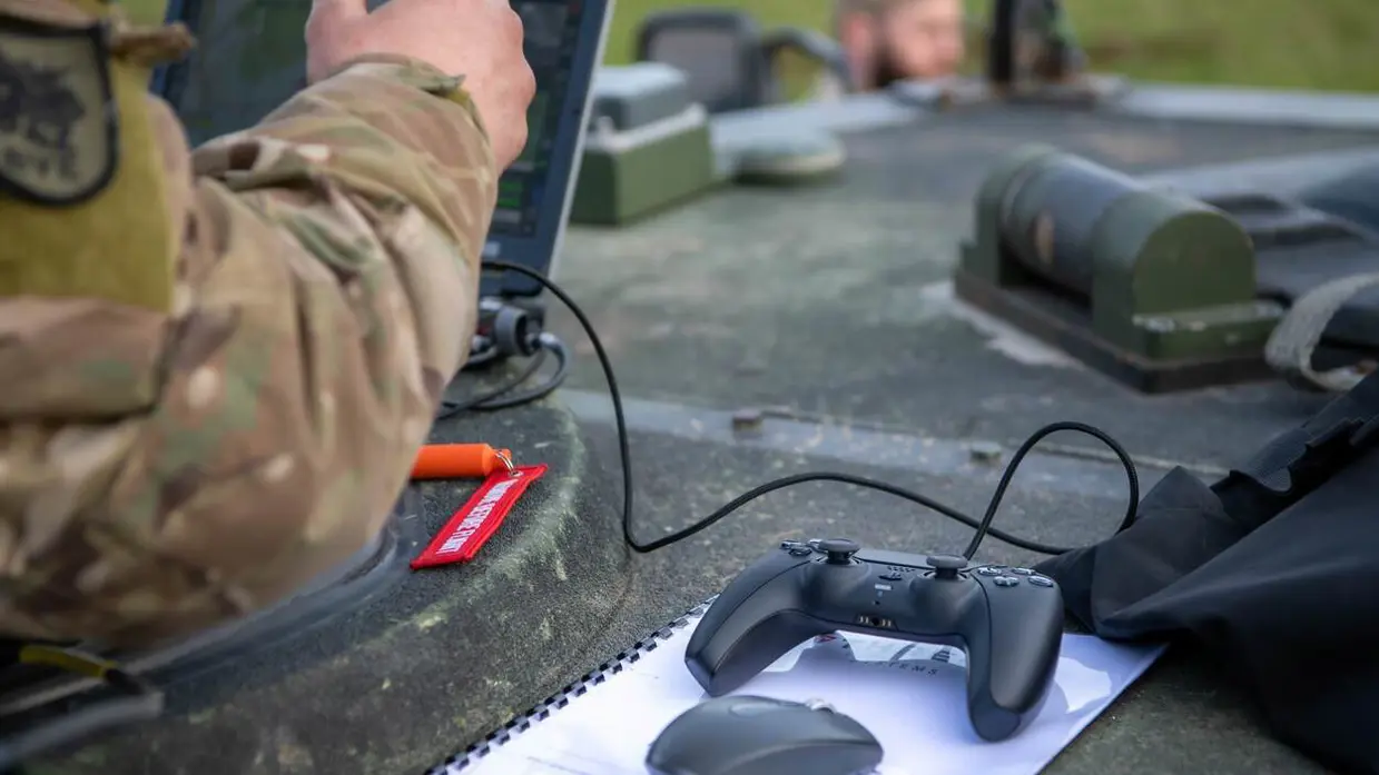 Militair op voertuig kijkt op scherm.
