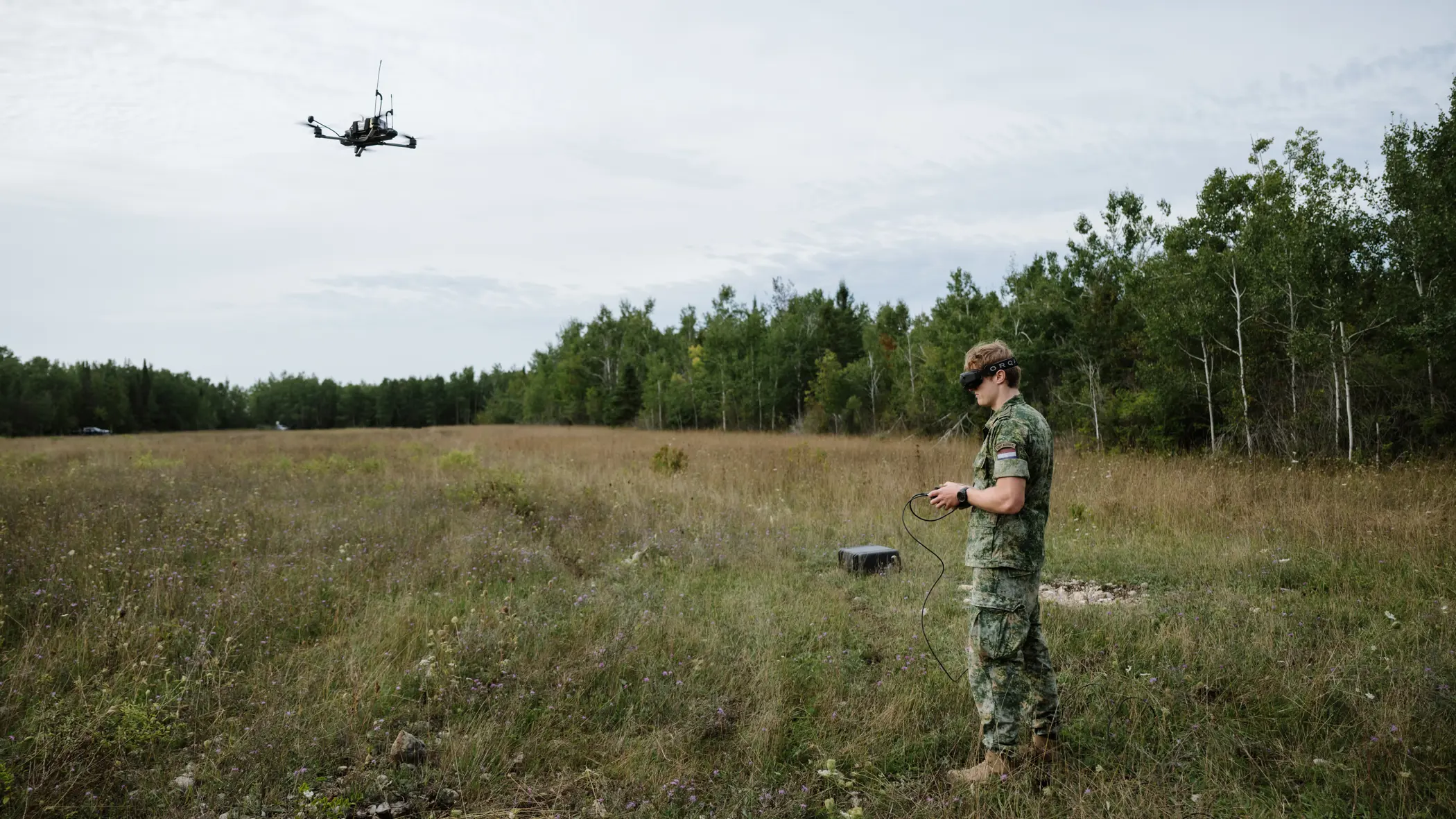 Een dronepiloot stuurt en volgt een drone met zijn controller en FPV-bril.