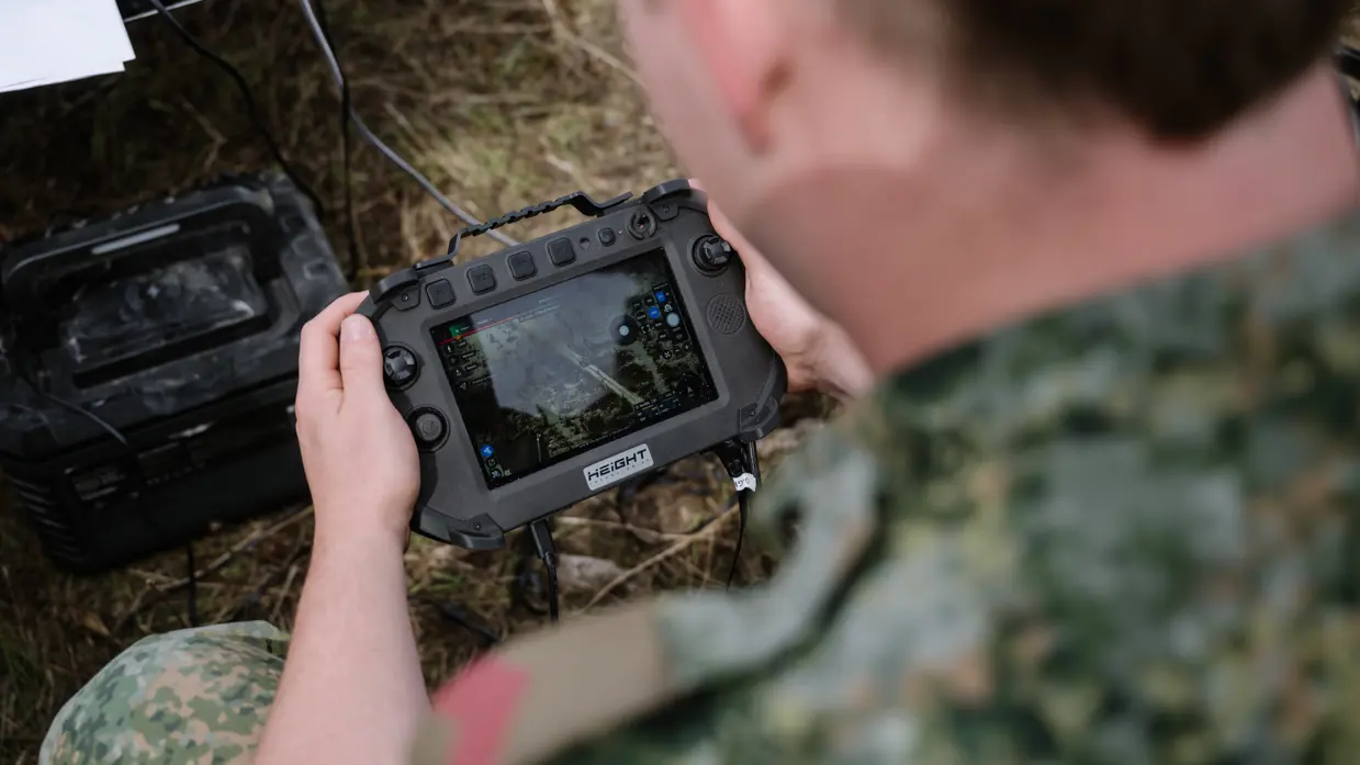 Een militair kijkt met controle stick op zijn FPV-monitor.