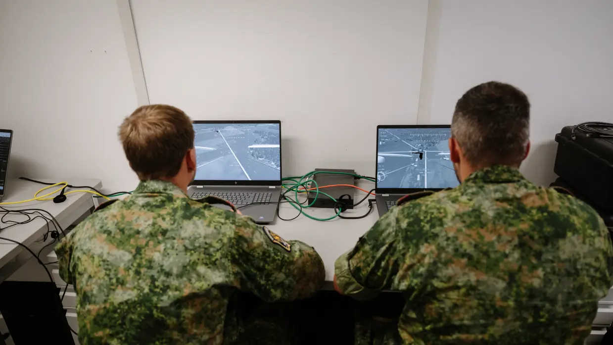 2 militairen aan een bureau kijken beiden op een beeldscherm.