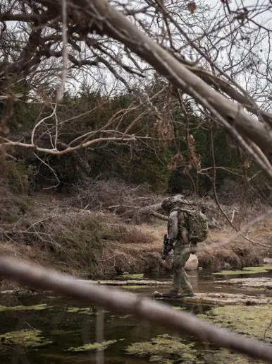 Militair steekt via lage rotsen een rivier over.