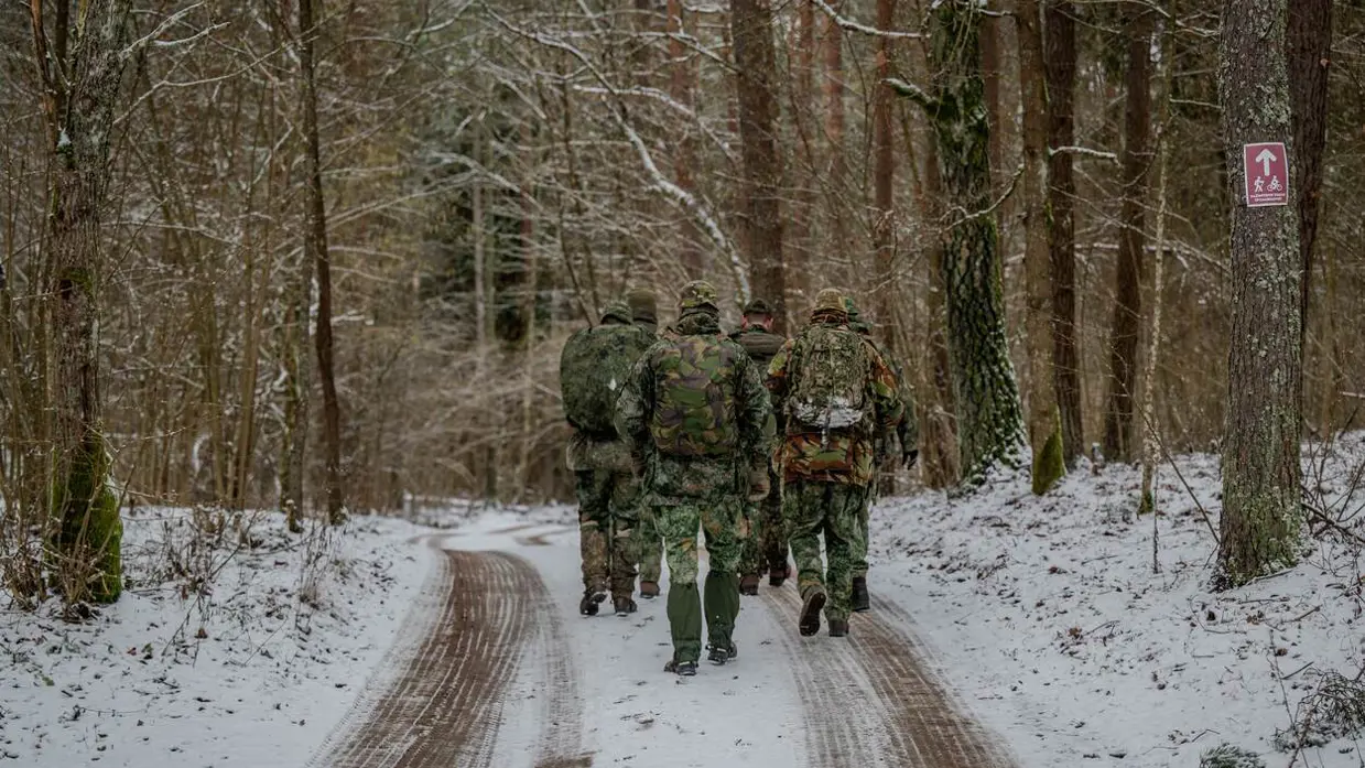 Soldaten lopen in de sneeuw door het bos.