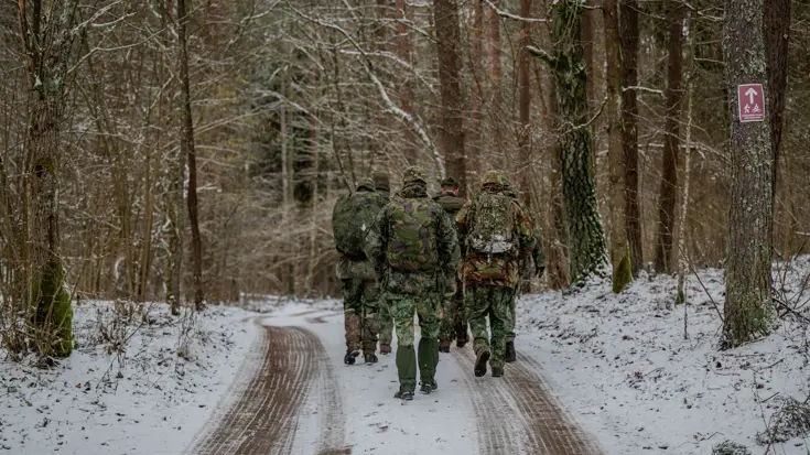 Soldaten lopen in de sneeuw door het bos.