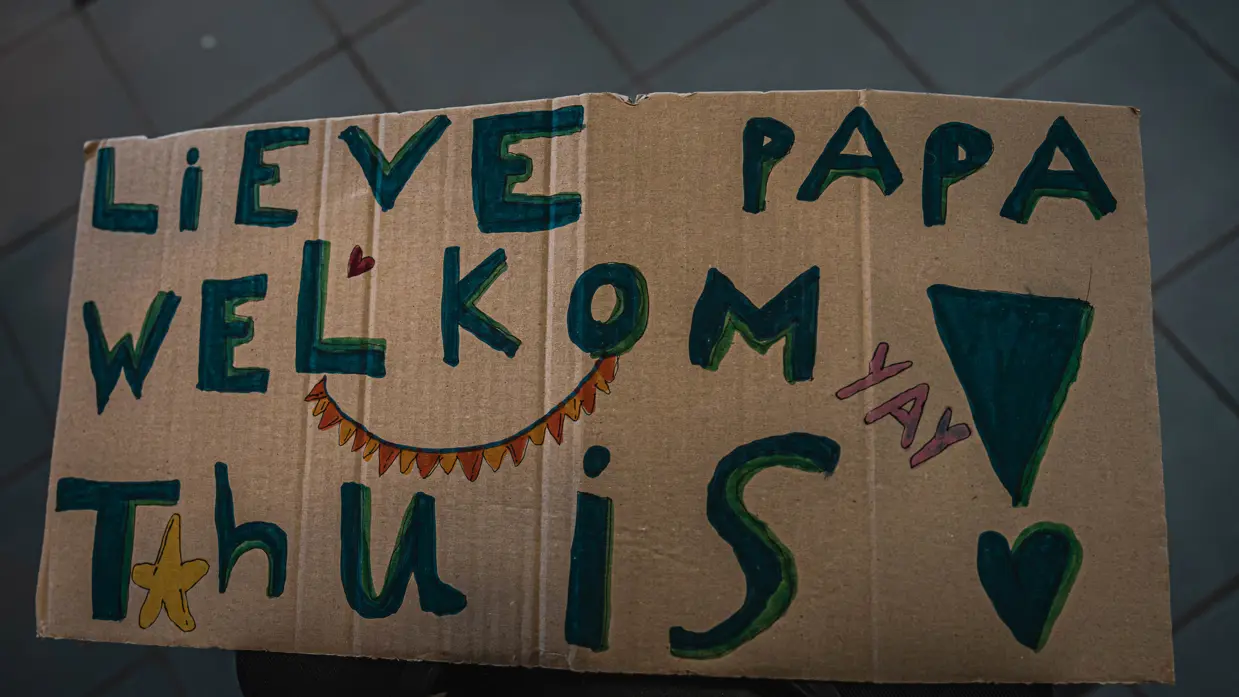 Kartonnen bord met tekst ‘Lieve papa welkom thuis!’.