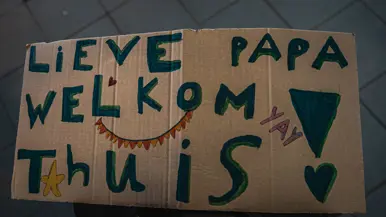 Kartonnen bord met tekst ‘Lieve papa welkom thuis!’.