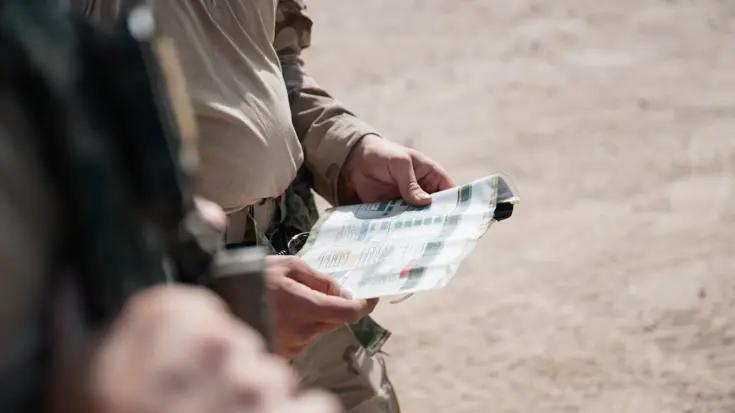 Militairen kijken op een geplastificeerd kaartje. 