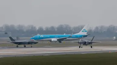 Twee F-35’s taxiën voor een KlM-vliegtuig langs