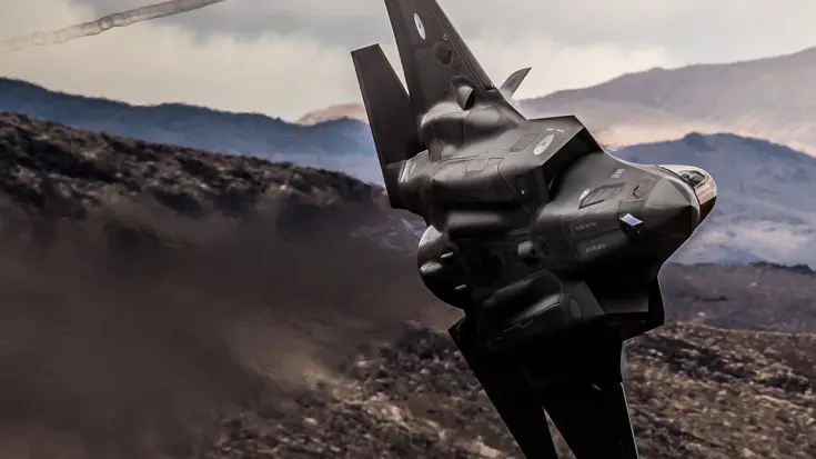 Een F-35 gevechtsvliegtuig scheert over een woestijn.