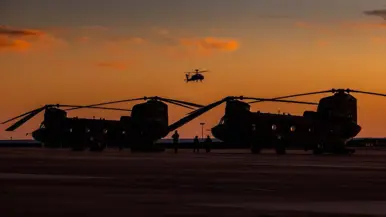 Twee Chinooks tegen het rode ondergaande zon.