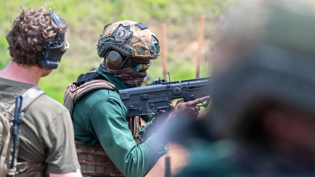 Een schietende Afrikaanse militair. Een Nederlandse collega kijkt over zijn schouder mee.
