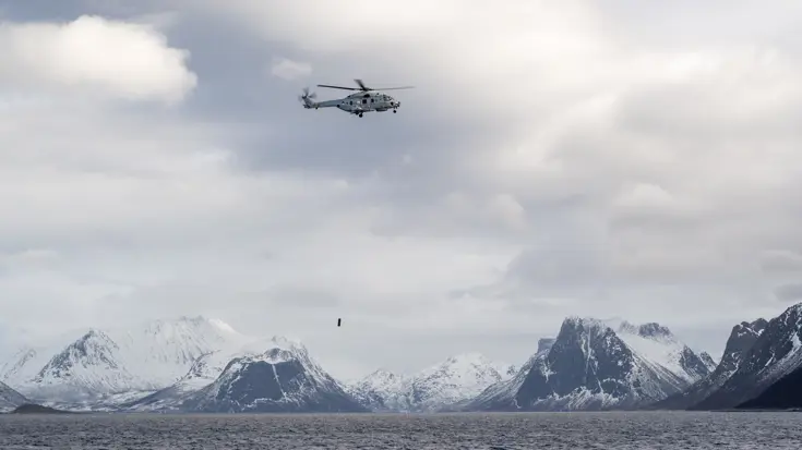 Alttekst: Een NH90 die tegen de achtergrond van besneeuwde rotsen haar sonar te water laat. &nbsp; &nbsp;&nbsp;