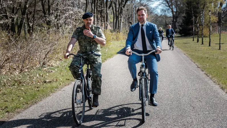 Staatssecretaris van Defensie Derk Boswijk op de fiets, net als een begeleider, tijdens een bezoek aan Nieuw-Milligen.