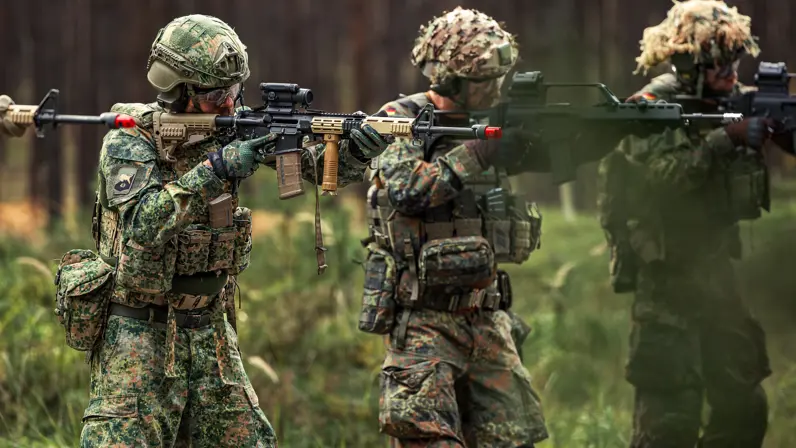militairen in camouflagepak en meet wapen staande naast elkaar.  