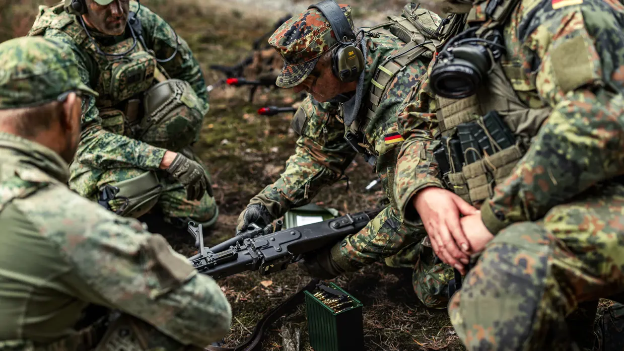  reservisten die zich buigen over een mitrailleur. 