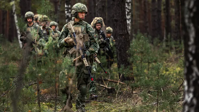 militairen met geweer lopend achter elkaar.  