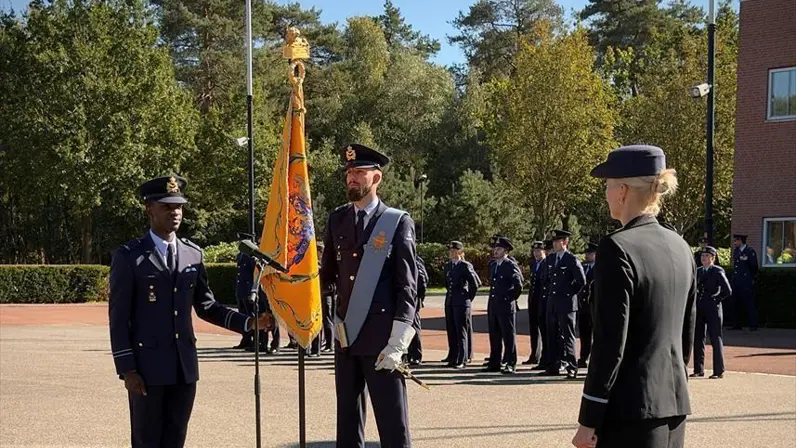 Een militair met de hand aan het vaandel van de luchtmacht.