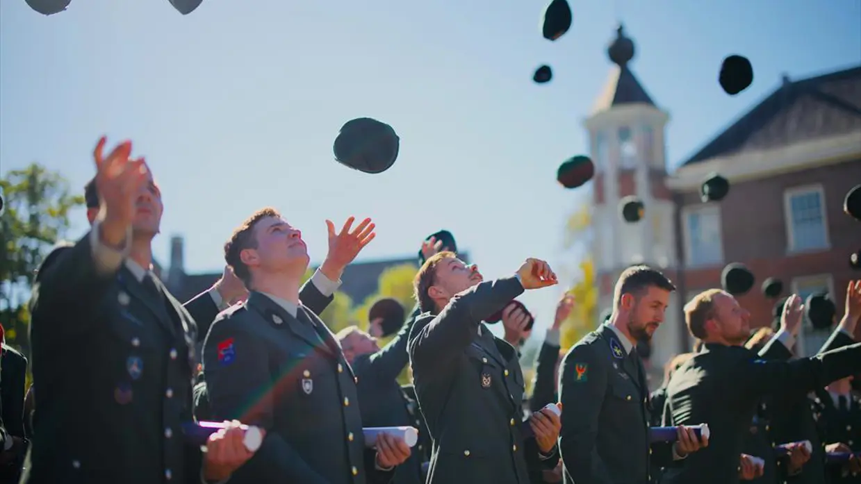 Militairen gooien hun pet omhoog.