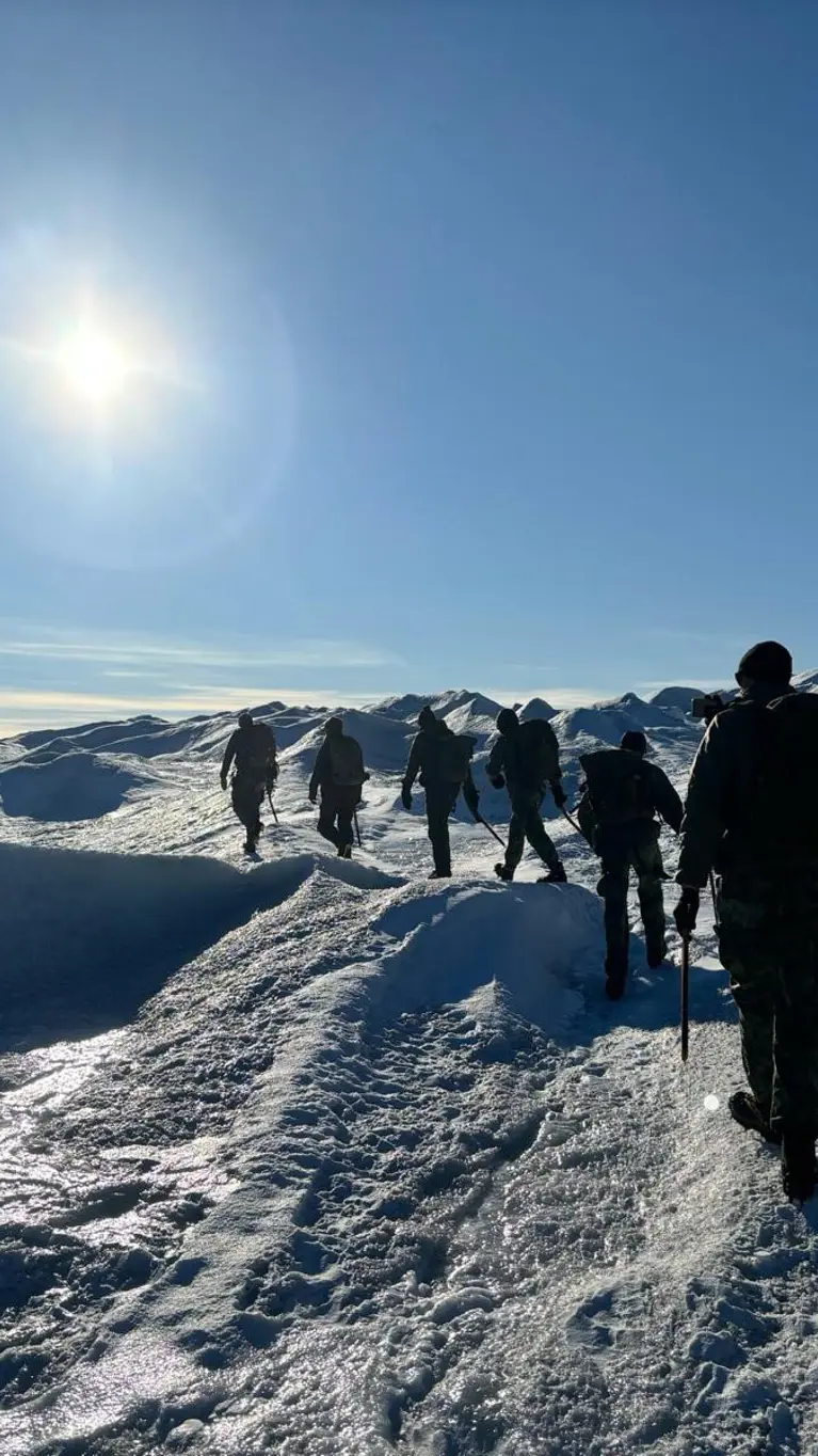 Mariniers achter elkaar lopend in een weids wit landschap.
