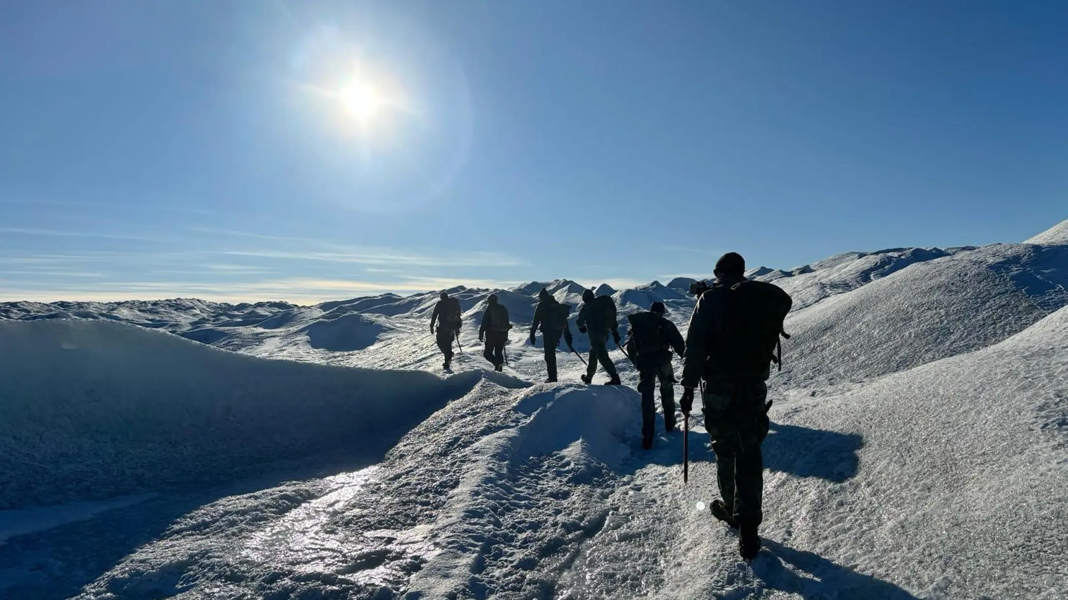 Mariniers achter elkaar lopend in een weids wit landschap.