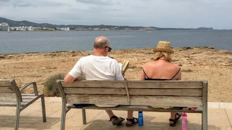 Twee personen zitten op het strand.
