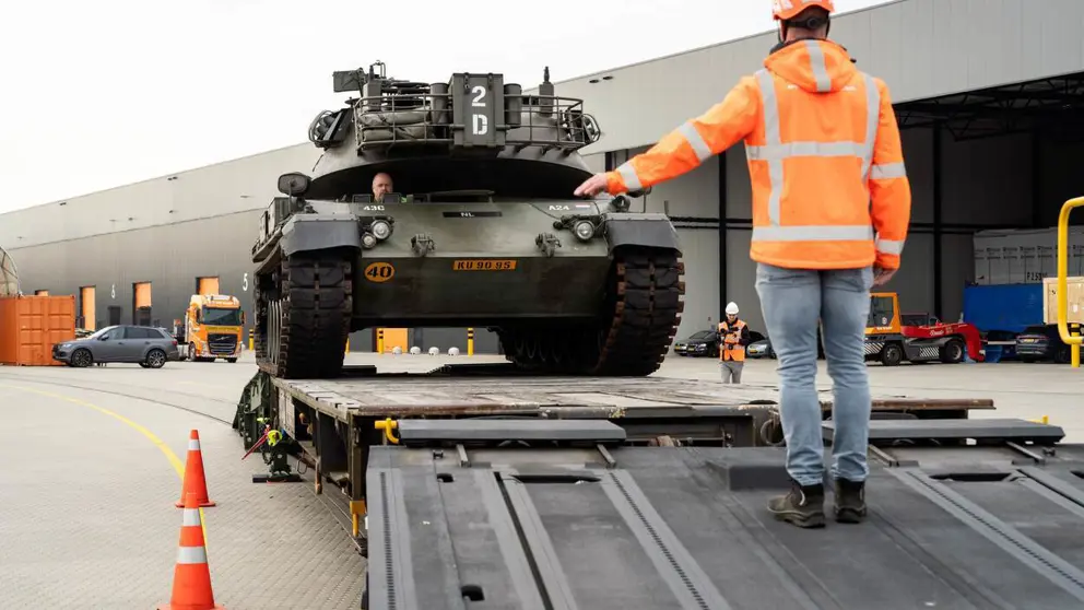 Militair voertuig wordt op een wagon gereden.
