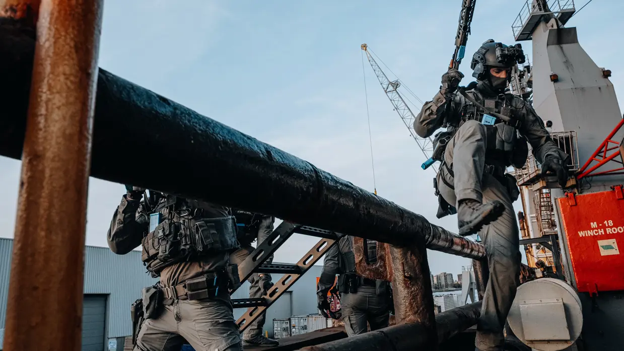 Een militair springt over een hekje. 