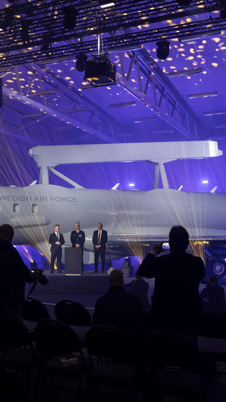 Onthulling van de eerste Zweedse Saab GlobalEye in een hangar met paars gekleurde lampen.