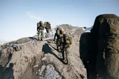 Militairen beklimmen met bepakking een berg.