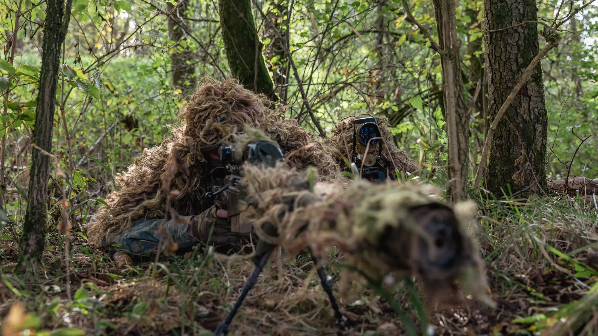 een sniper en een spotter verscholen onder gebladerte&nbsp;