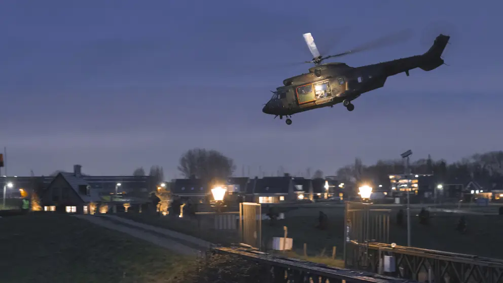 Helikopter bij schemer boven bewoond gebied.