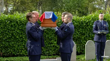 Luchtmachtmilitairen dragen de kist bij het graf.