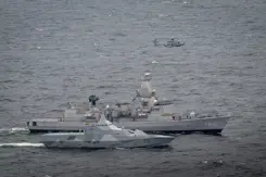 Een Zweedse schip met daarachter de Van Amstel en daarboven een NH90-helikopter.
