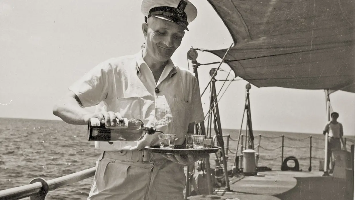  Een hofmeester serveert drankjes op het dek van een marineschip in 1948.