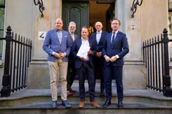 De staatssecretaris poseert met 4 mannen op de trap van het ministerie.