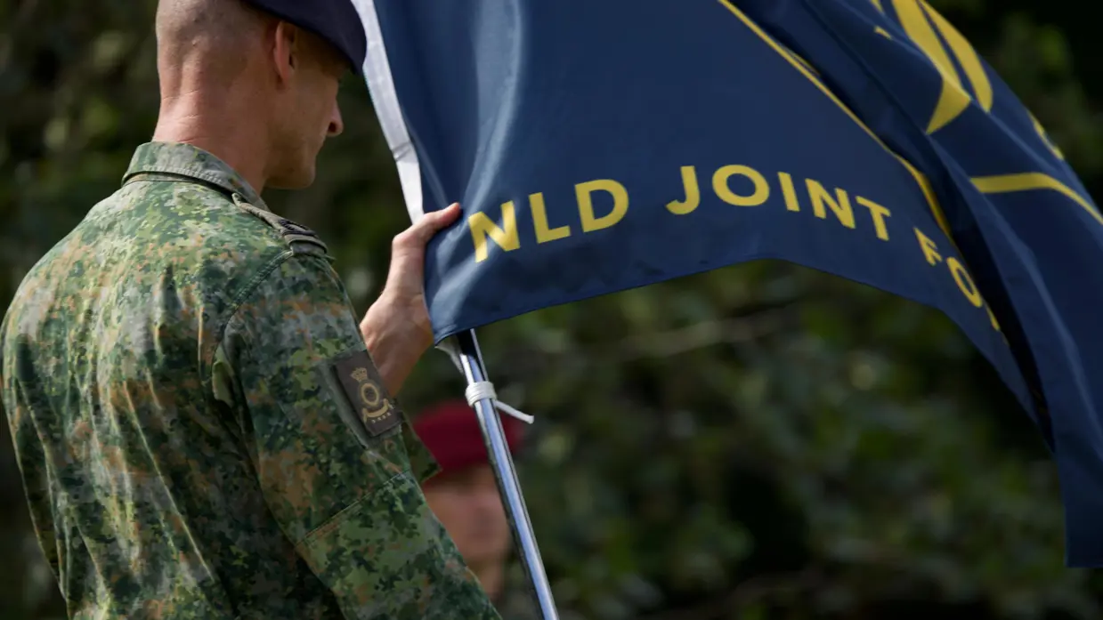 Een militair houdt de vlag van JFC vast. 