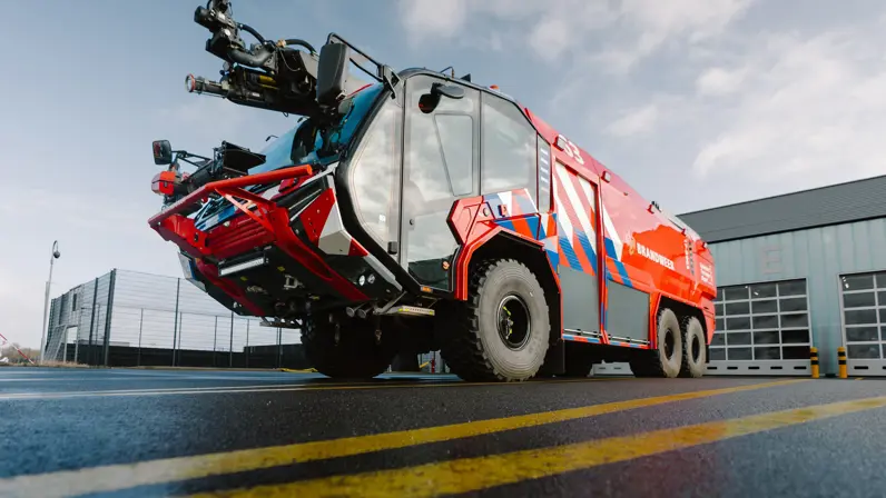Rood blusvoertuig Rosenbauer Panther 6x6 voor een garagebox. 