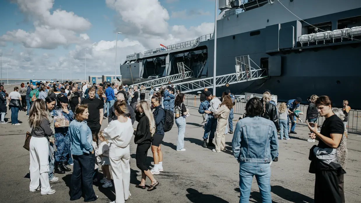 Familie en vrienden zwaaien de bemanning uit op de kade.