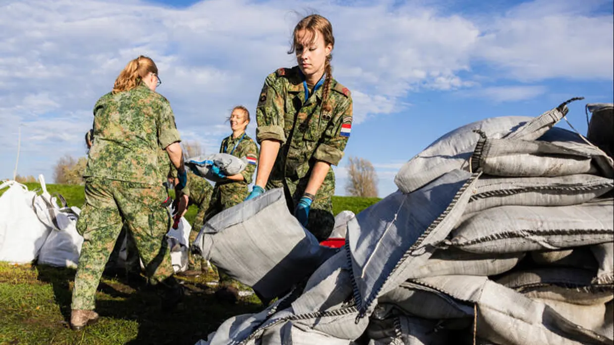 Vrouwelijke militair verplaatst een zandzak.