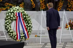 De koning staat voor de krans bij het monument. 