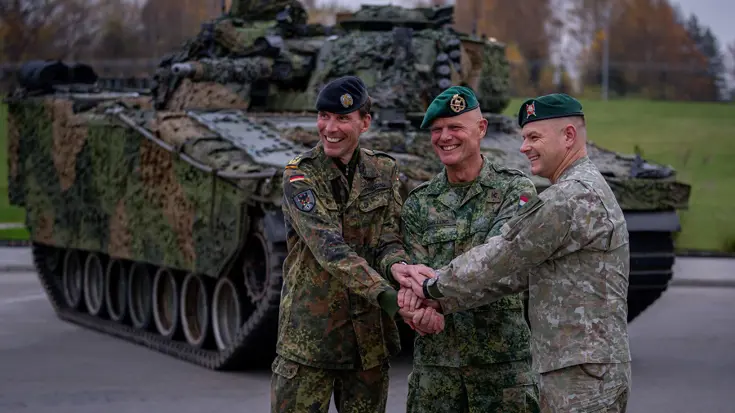 Christian Freuding, Jan Swillens en de commandant van de Litouwse strijdkrachten met de handen op elkaar voor een tank.
