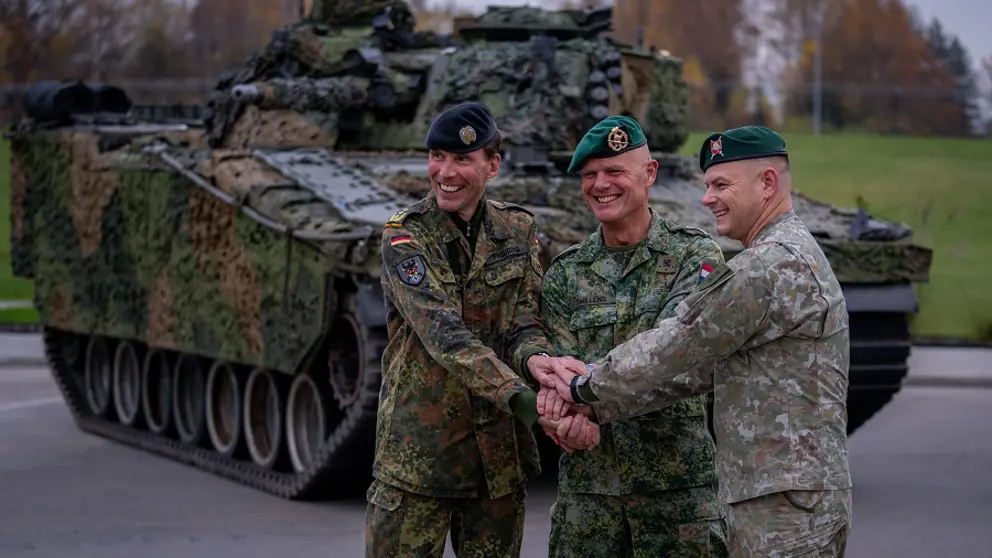 Christian Freuding, Jan Swillens en de commandant van de Litouwse strijdkrachten met de handen op elkaar voor een tank.